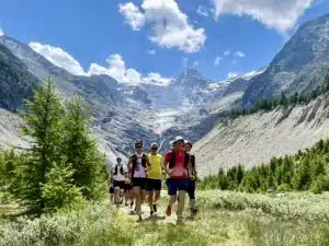 Mehrere Läufer in imposanter Berglandschaft umgeben von kleinen, grünen Bäumen.
